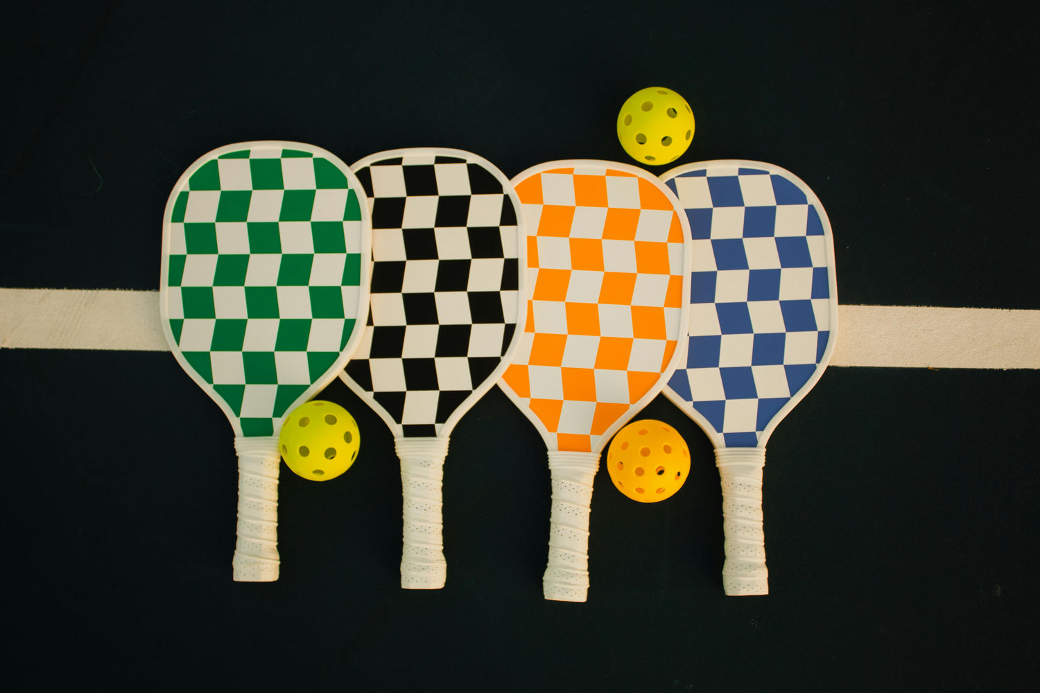 Four checkerboard printed pickleball paddles and three pickleball balls