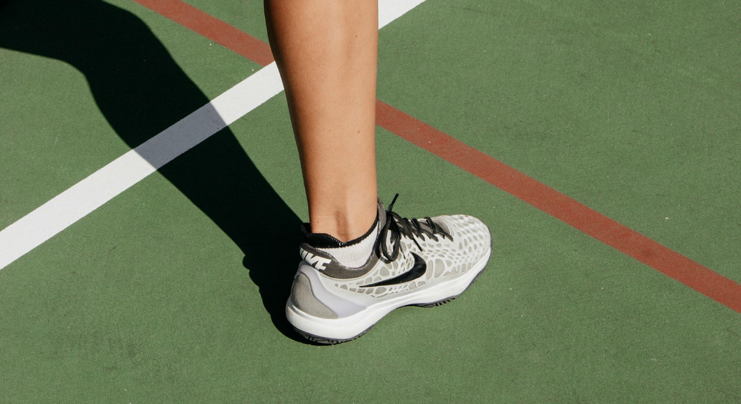 Foot with court shoe on standing on pickleball court