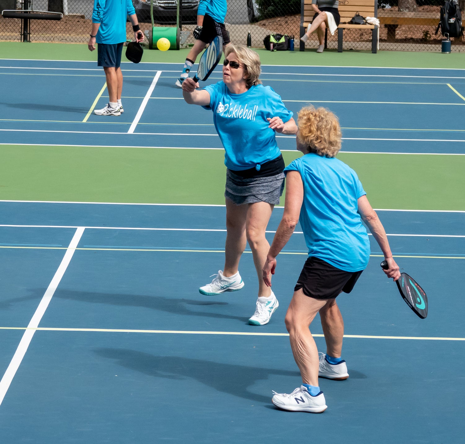 Two women playing pickleball and practicing with some drills.