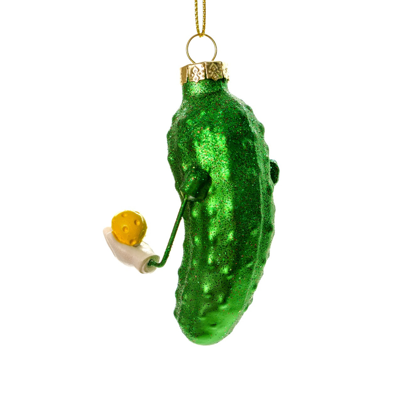 The back of a cute handmade Kurt Adler Christmas ornament of a pickle holding a pickleball paddle and a pickleball on a white studio backdrop