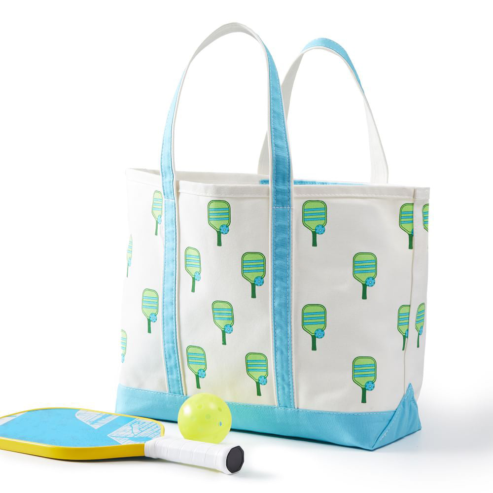 Canvas tote bag with pickleball paddles printed on it and teal handles with a pickleball paddle and ball outside of the bag