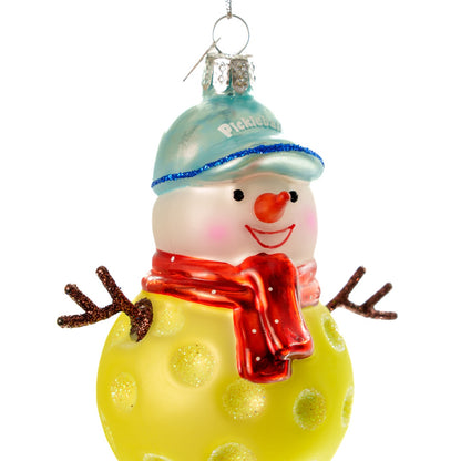 Close up of an elegant handmade glass Christmas ornament of a pickleball snowman on a white studio backdrop