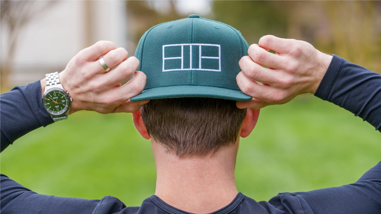 Man wearing backwards flat-brimmed hat with pickleball court outline