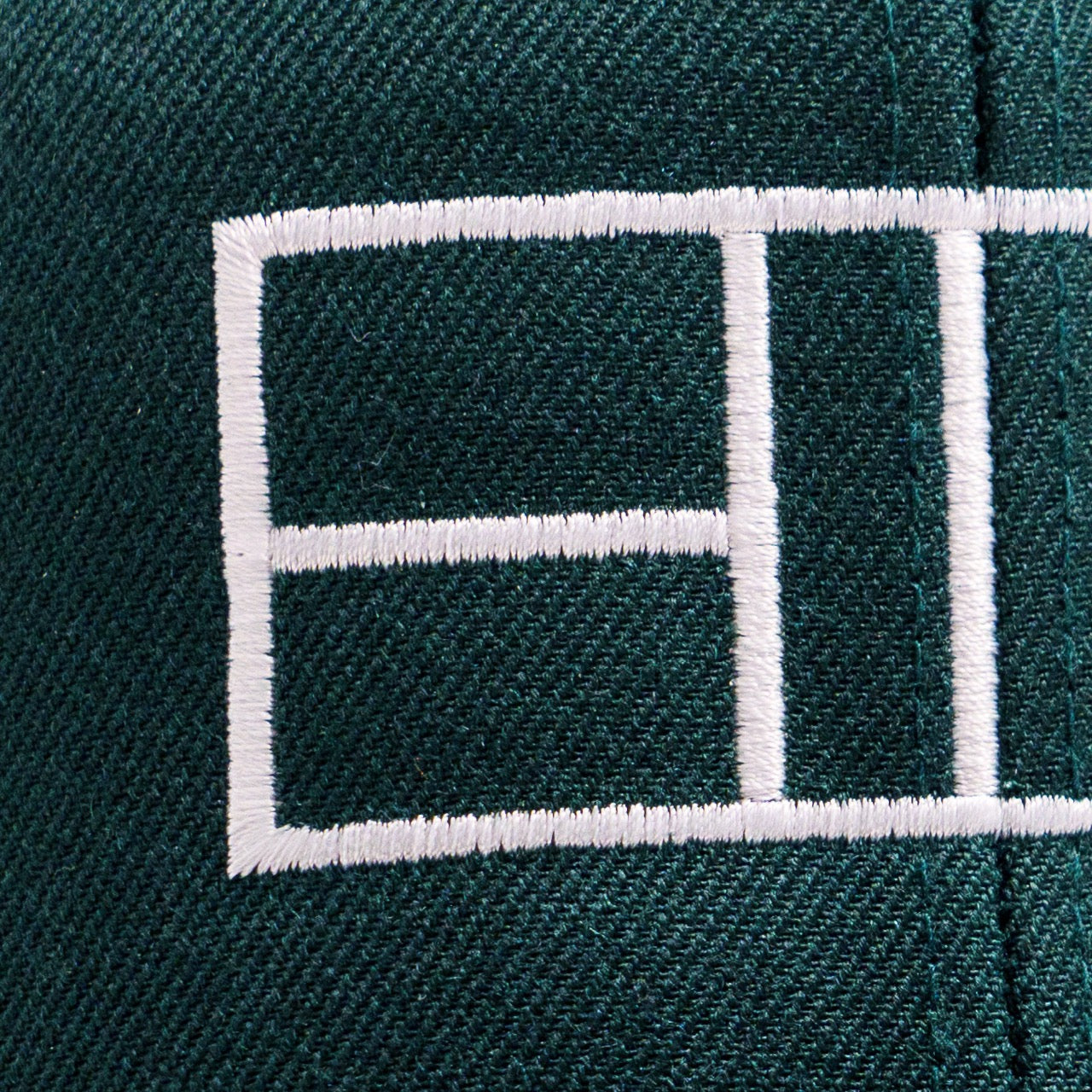 A detailed view of the embroidered pickleball court lines on a green hat