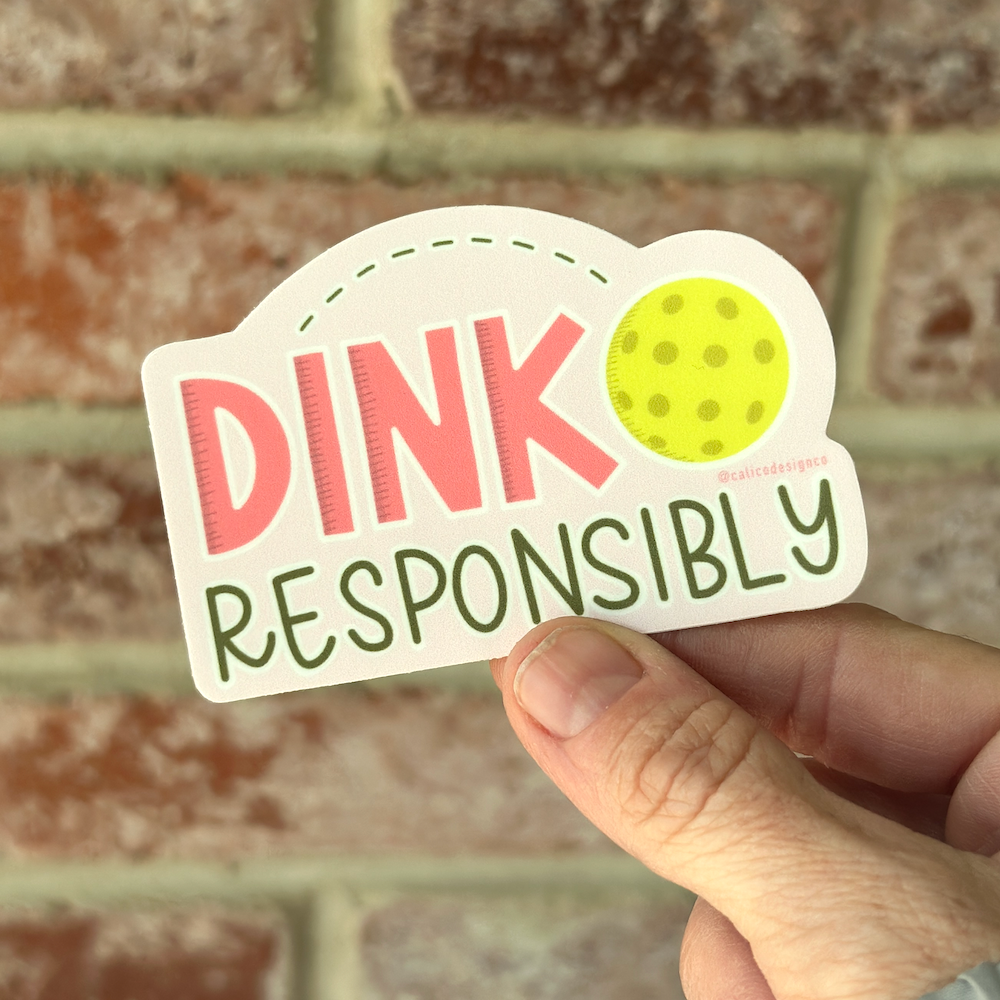 Dink Responsibly Sticker being held in front of brick wall