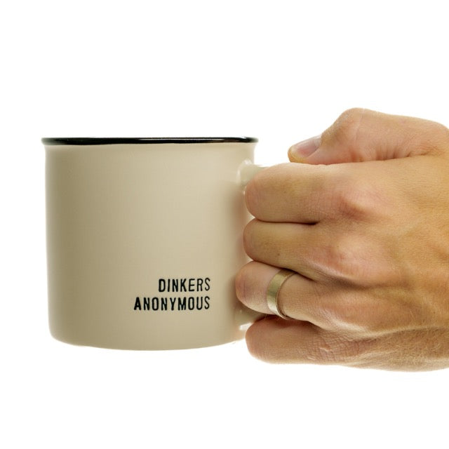 Humorous stoneware coffee mug that says Dinkers Anonymous on it being held by a man.