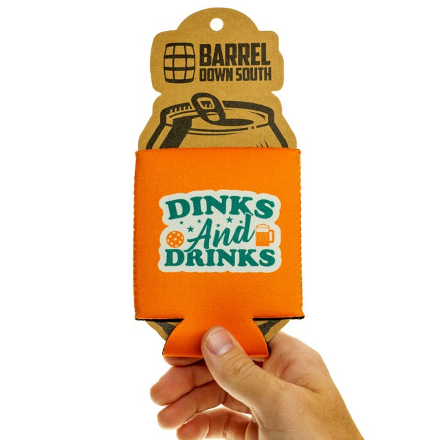 Orange drink coozie that says Dinks and Drinks on it being held in hand