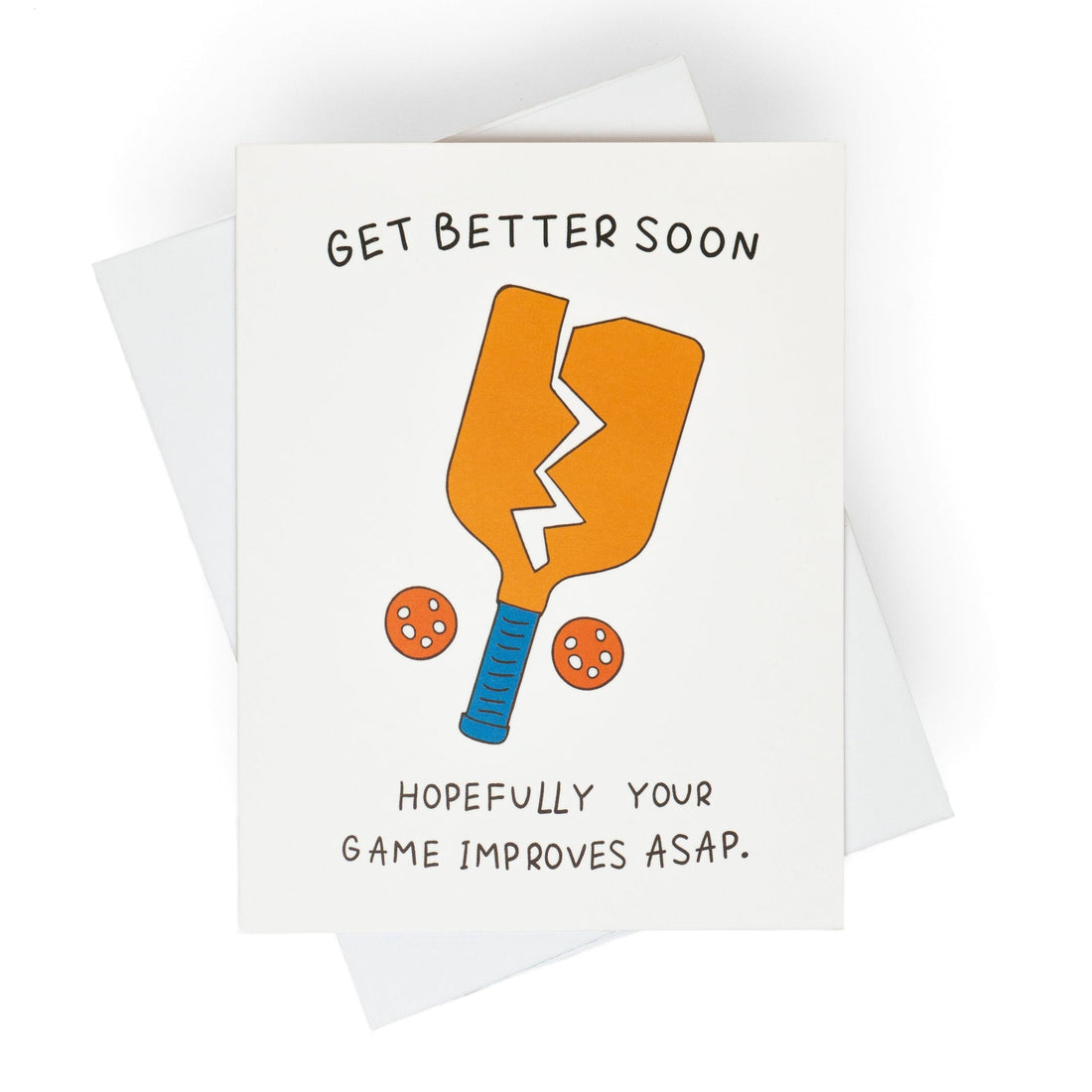 Funny pickleball themed get well soon greeting card that shows a broken paddle and two pickleballs with text that reads &quot;Get Better Soon, Hopefully your game improves ASAP.&quot; laying flat on a studio backdrop.