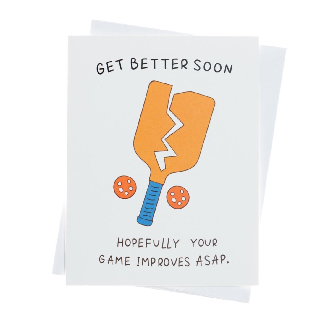 Funny pickleball themed get well soon greeting card that shows a broken paddle and two pickleballs with text that reads &quot;Get Better Soon, Hopefully your game improves ASAP.&quot; laying flat on a studio backdrop.