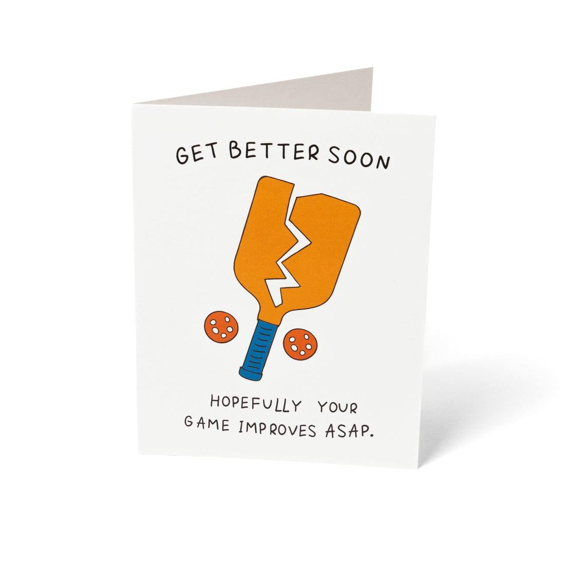 A funny pickleball themed get well soon greeting card that shows a broken paddle and two pickleballs with text that reads &quot;Get Better Soon, Hopefully your game improves ASAP.&quot; standing up in front of a white background