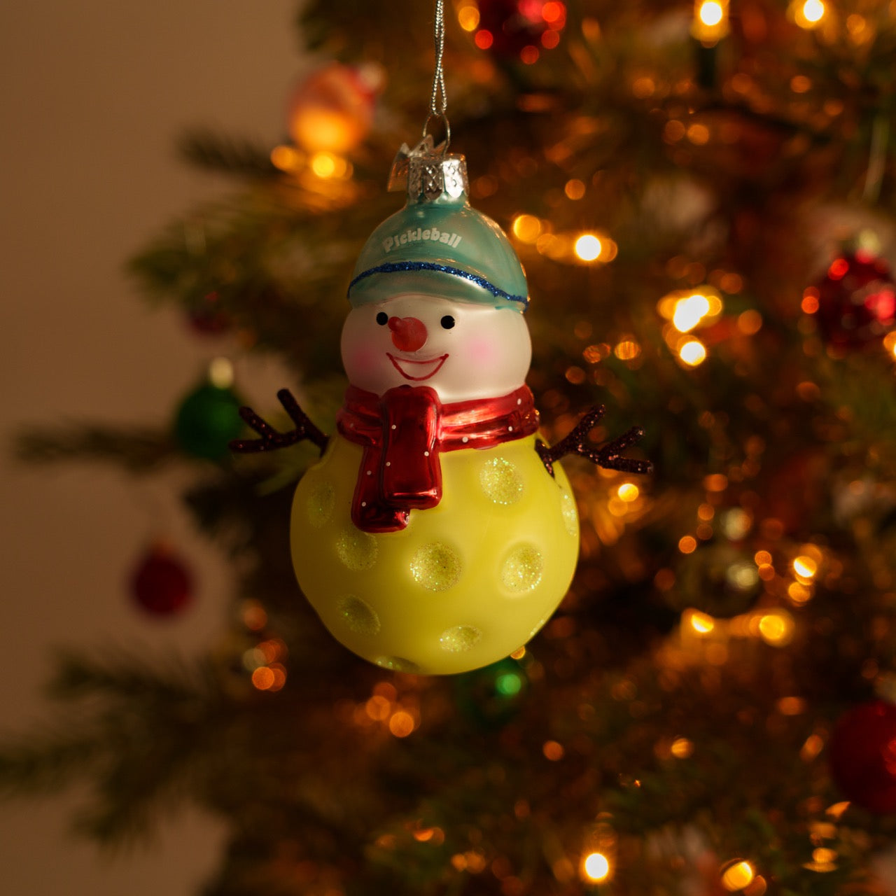 Elegant handmade glass Christmas ornament of a pickleball snowman on a Christmas tree