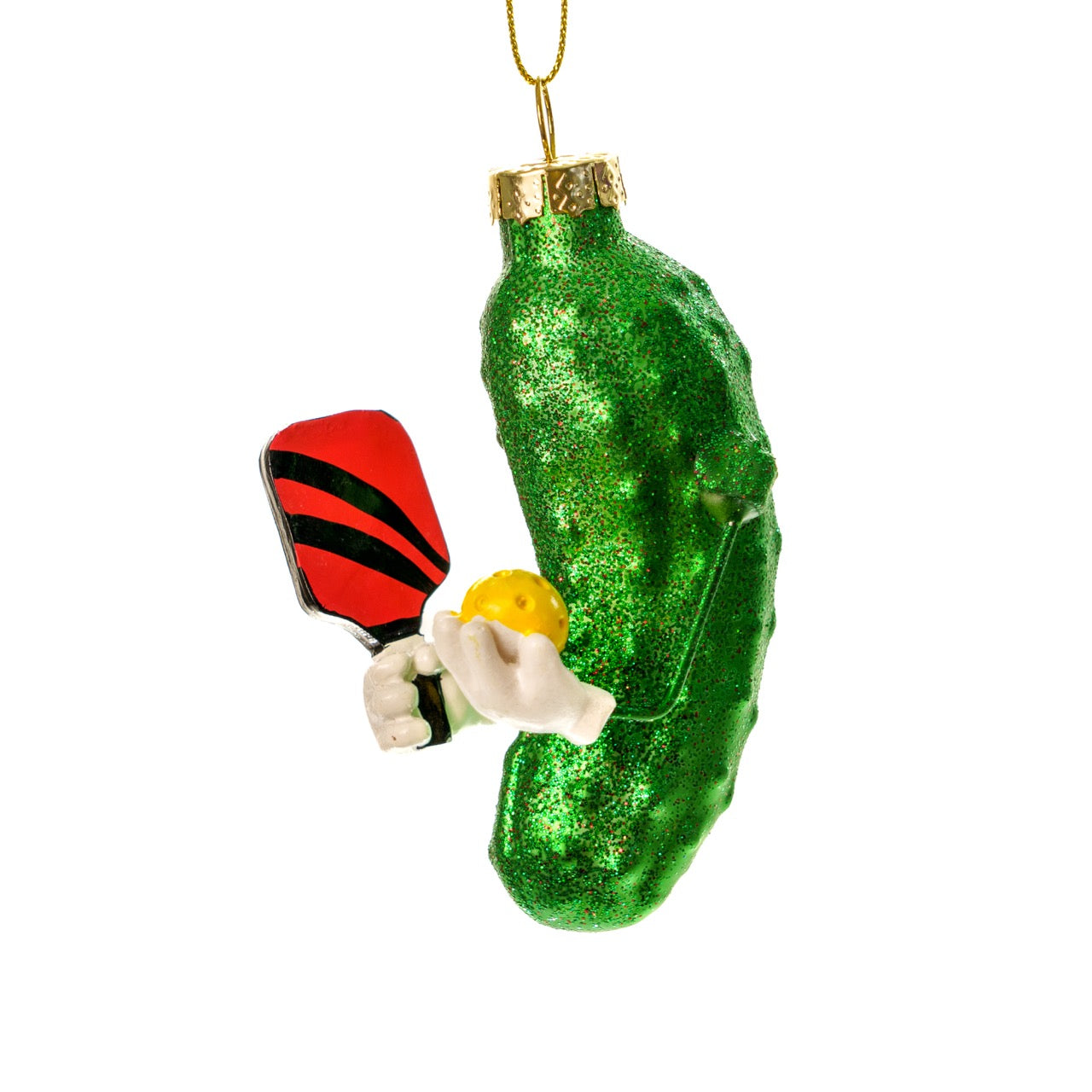 Left side of a fun handmade Kurt Adler Christmas ornament of a pickle holding a pickleball paddle and a pickleball on a white studio backdrop