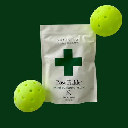 Packaging of post pickleball magnesium recovery soak on a green background with two pickleballs