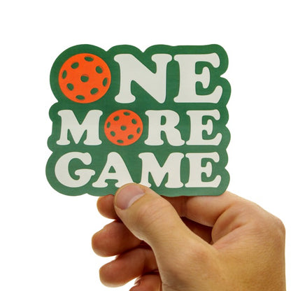 Sticker that says One More Game and has pickleballs on it being held in hand