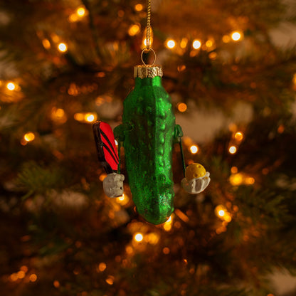 Handmade Kurt Adler Christmas ornament of a pickle holding a pickleball paddle and a pickleball on a Christmas tree