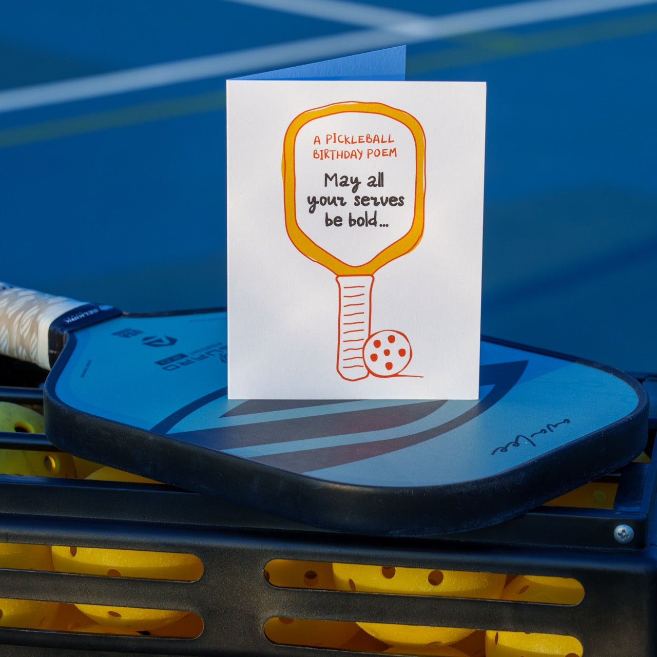 A funny pickleball birthday card with a pickleball paddle and ball that says &quot;A Pickleball Birthday Poem: May all your serves be bold...&quot; standing up on a pickleball paddle and pickleballs