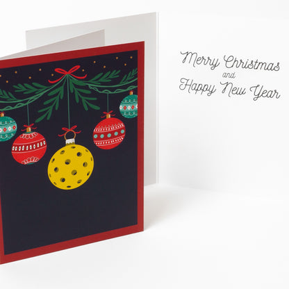 Inside and cover of a pickleball themed Christmas greeting card with hanging ornaments with a message saying &quot;Merry Christmas and Happy New Year&quot;