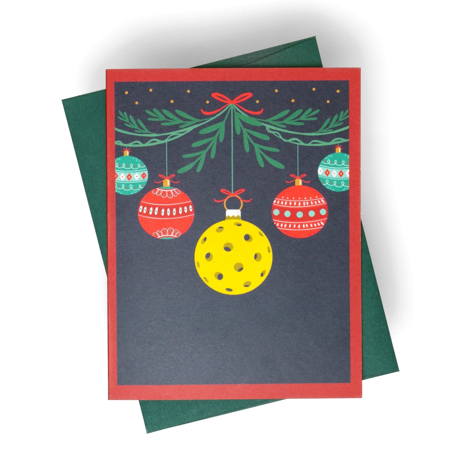 Pickleball themed Christmas greeting card with hanging ornaments and a pickleball with a green envelope laying flat