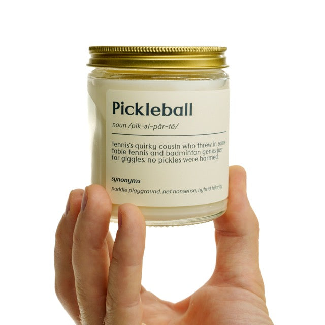 Pickleball definition candle with a cream label being held