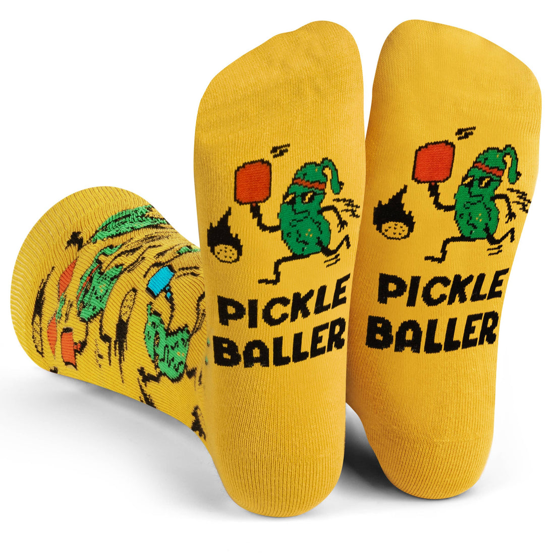 Soles of humorous yellow socks with pickles playing pickleball and say PICKLEBALLER on them being worn