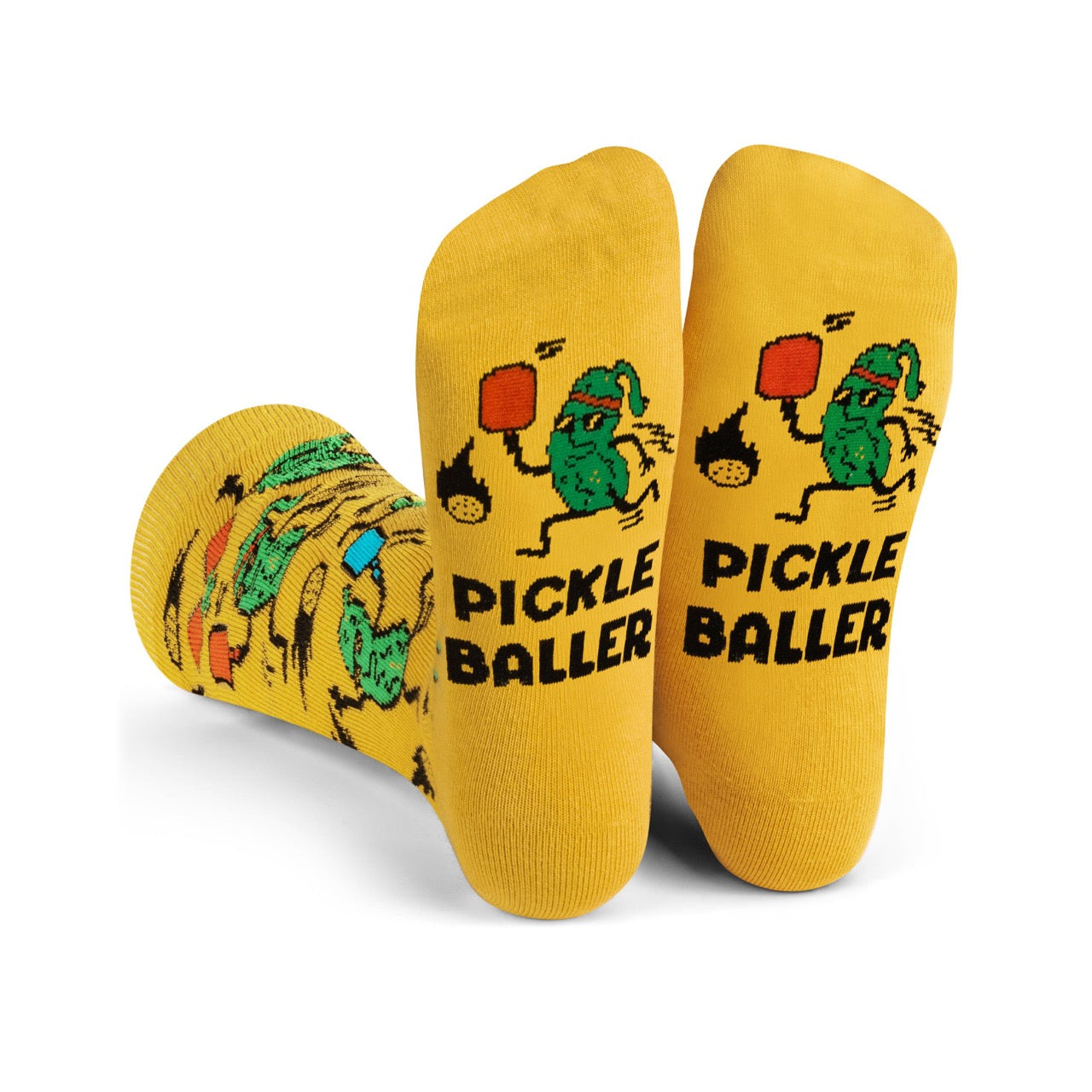 Soles of humorous yellow socks with pickles playing pickleball and say PICKLEBALLER on them being worn