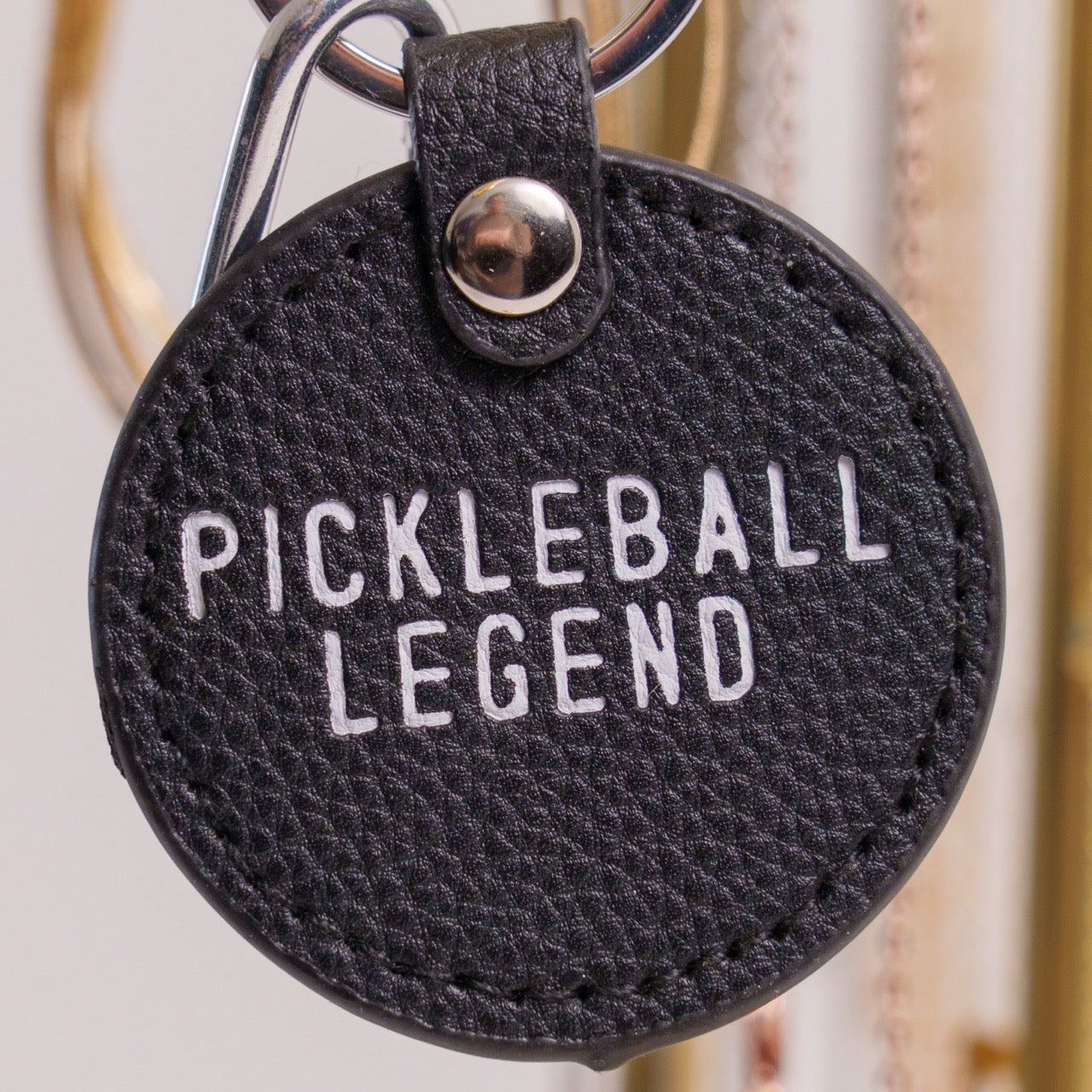 Black keychain that says Pickleball Legend on it hanging on jewelry holder up close