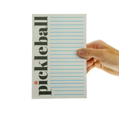 Lined notepad with the word Pickelball in large font down the side being held vertically