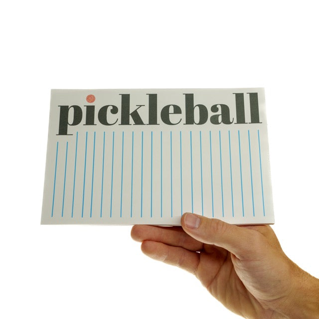 Lined notepad with the word Pickelball in large font down the side being held horizontally