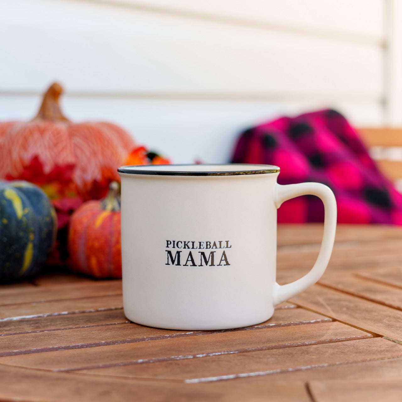 Stoneware mug that says Pickleball Mama on a table in front of pumpkins and a blanket