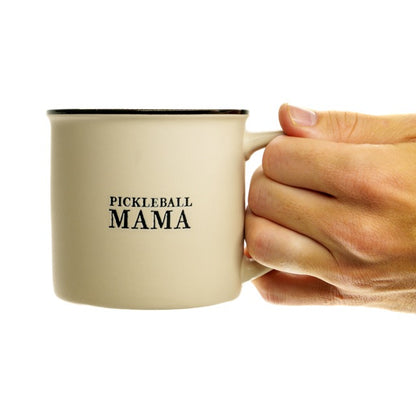 Stoneware coffee mug that says Pickleball Mama on it being held by a hand