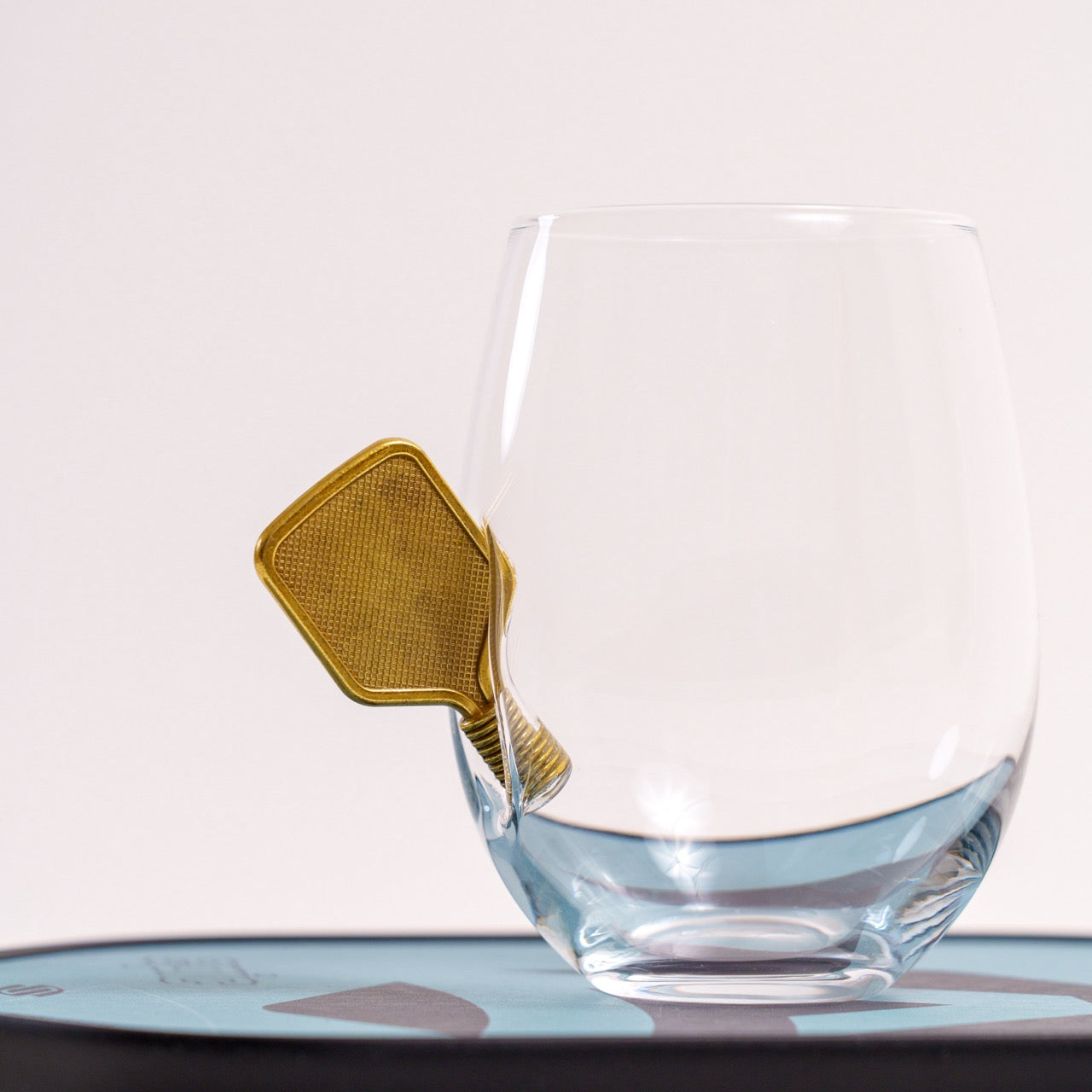 Wine glass with a metal pickleball paddle embedded in the side from the back