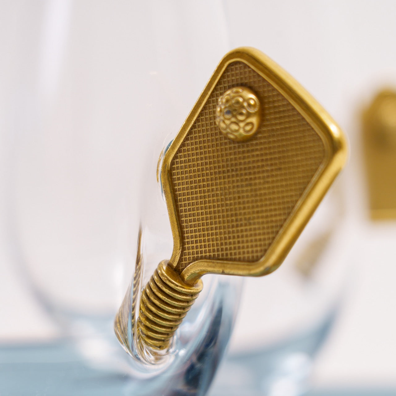 Wine glass with a metal pickleball paddle embedded in the side up close