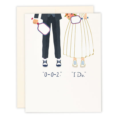 An elegant pickleball themed wedding card that shows a bride and a groom on their wedding day holding pickleball paddles wearing court shoes with text that reads &quot;0-0-2.&quot;, &quot;I Do.&quot;, laying flat on a white background.