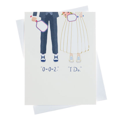 An elegant pickleball themed wedding card that shows a bride and a groom on their wedding day holding pickleball paddles wearing court shoes with text that reads &quot;0-0-2.&quot;, &quot;I Do.&quot;, laying flat on a white background.