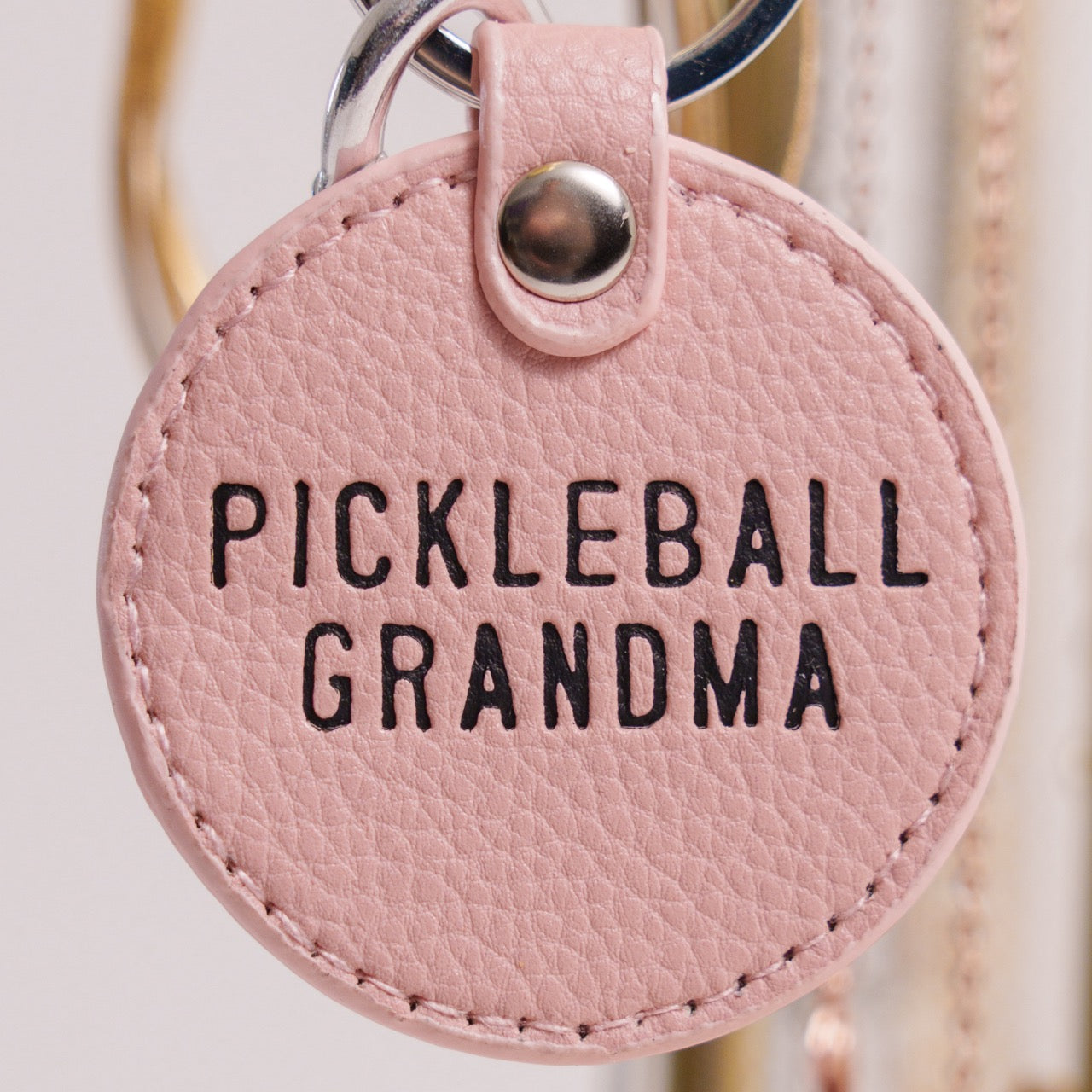 Pink keychain that says Pickleball Grandma on it hanging on jewelry holder