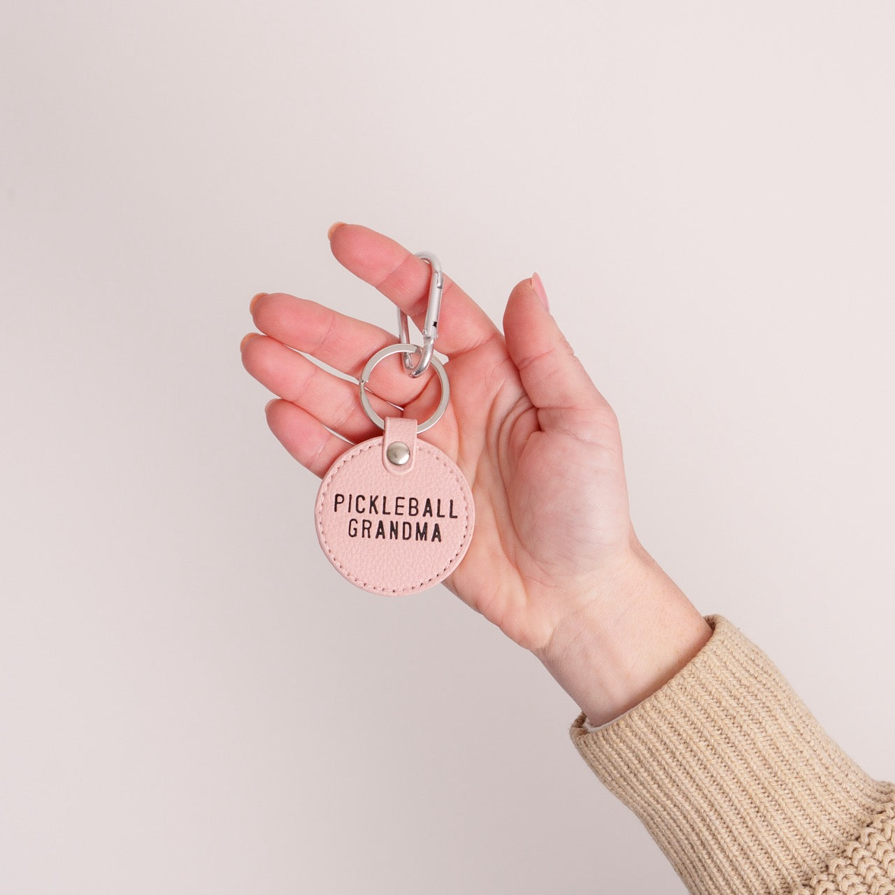 Pink keychain that says Pickleball Grandma on it being held