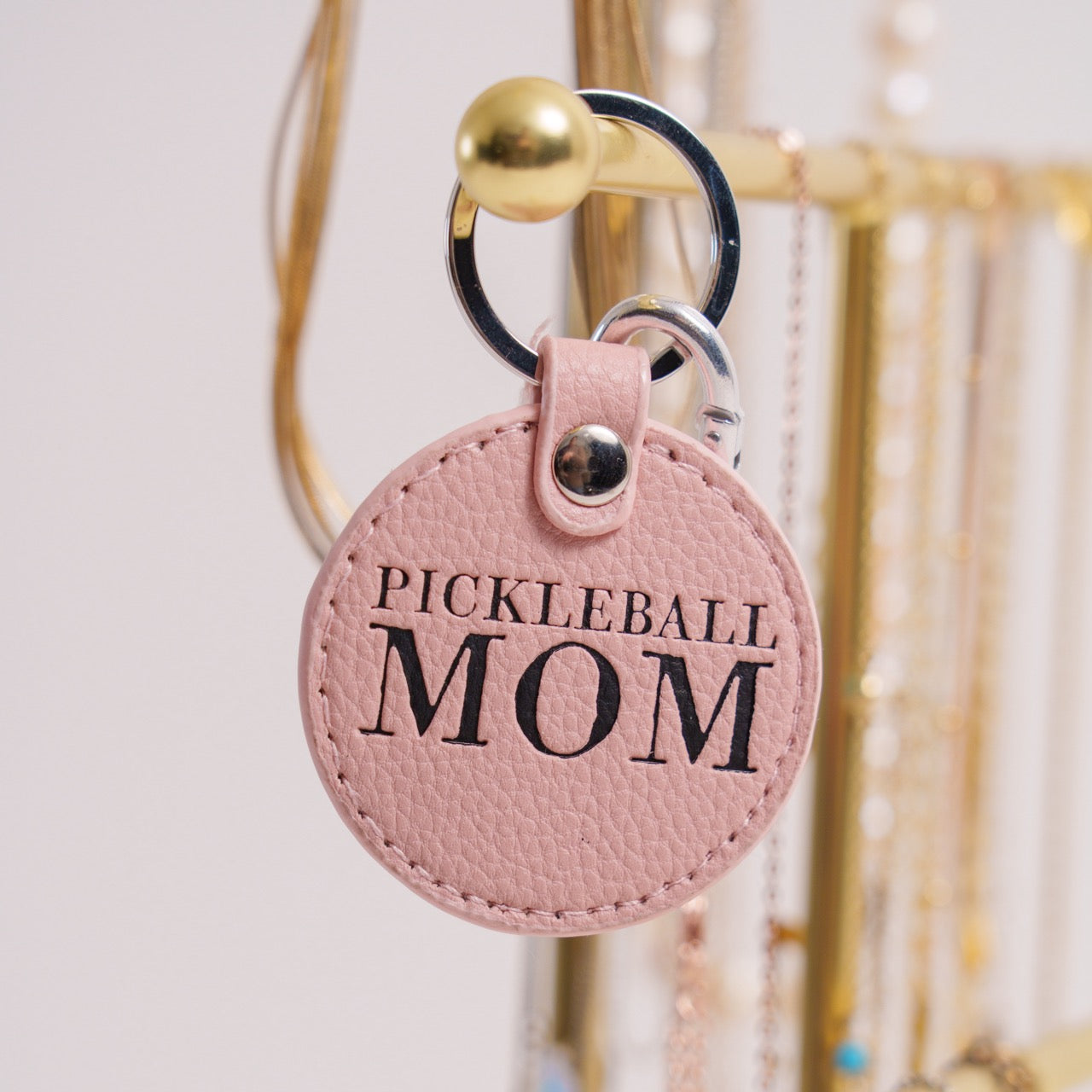 Pink keychain that says Pickleball Mom on it hanging on jewelry holder