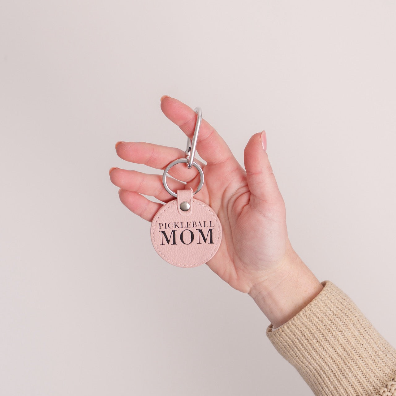 Pink keychain that says Pickleball Mom on it being held