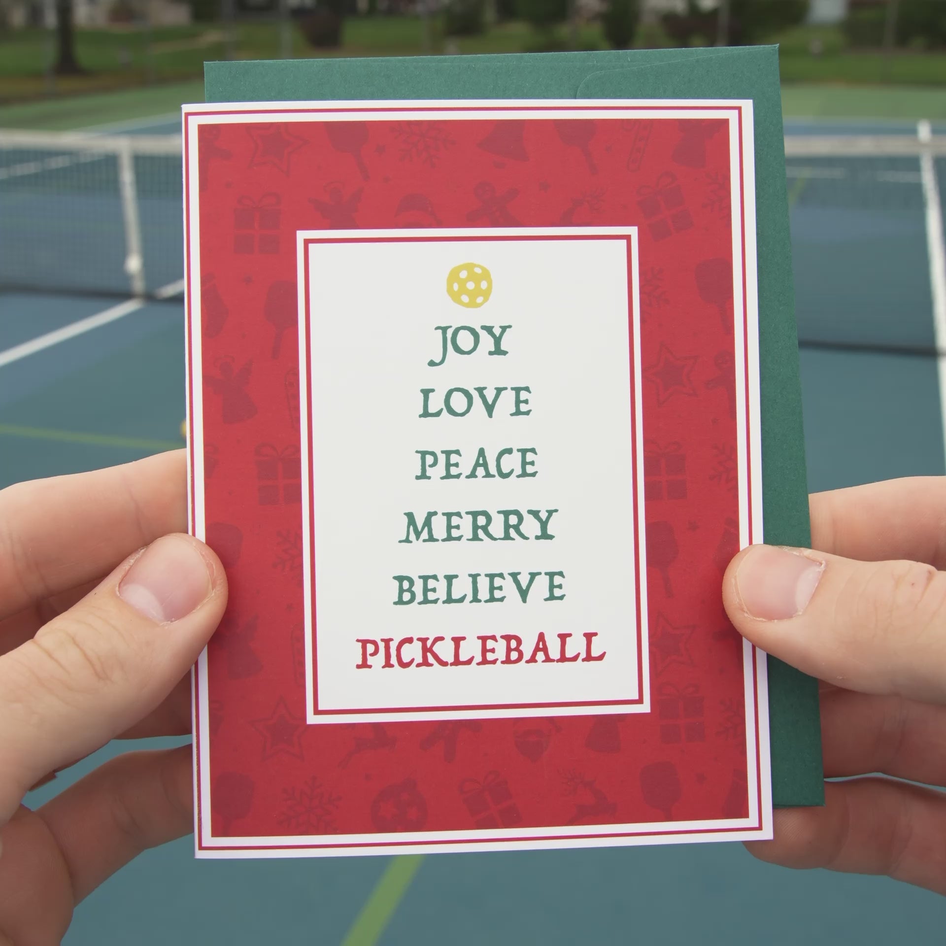 Video of a festive pickleball themed Christmas card featuring Christmas themed words stacked to look like a Xmas tree with a yellow pickleball at the top