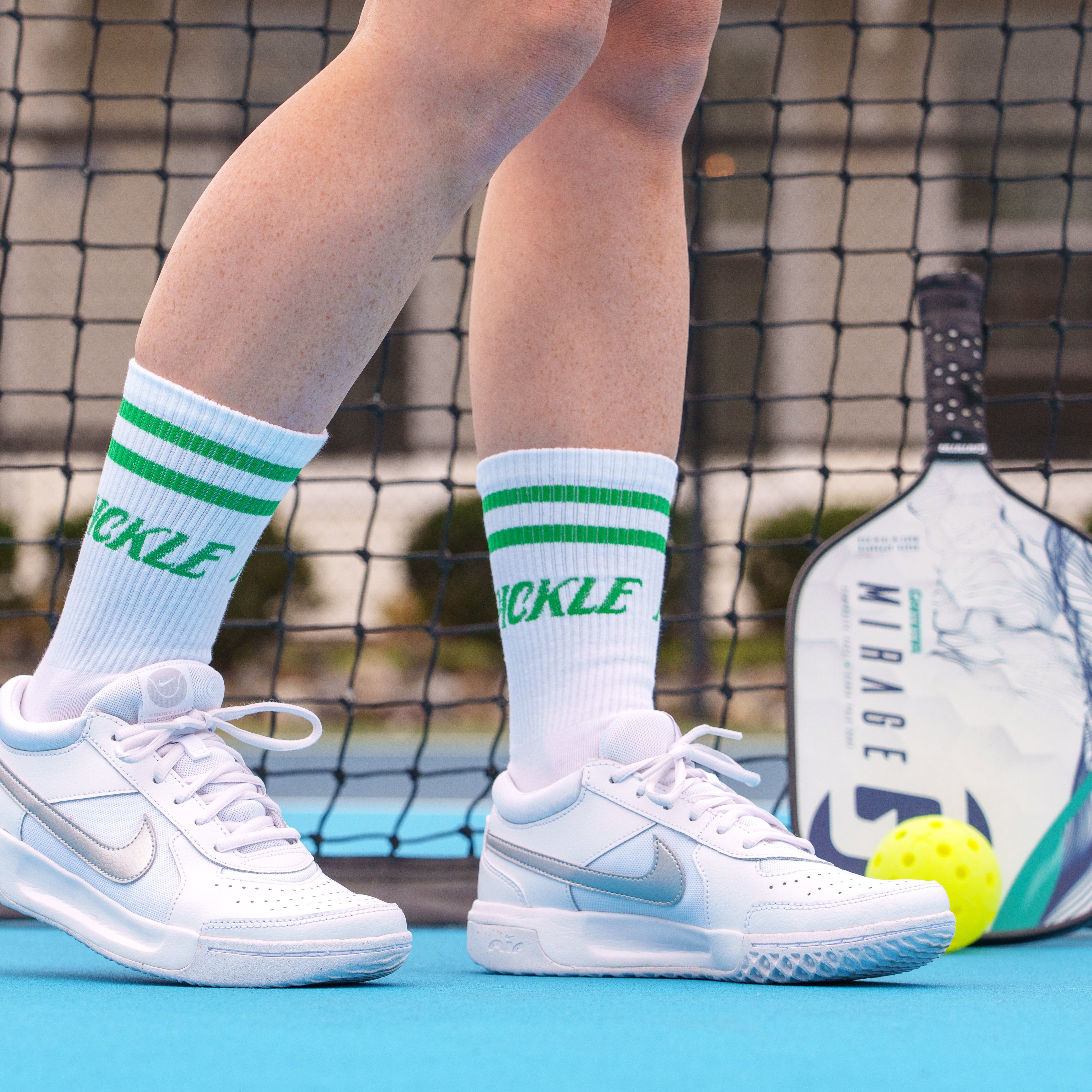 Person wearing retro pickleball cotton spandex mid-calf socks that say &quot;PICKLE&quot; on them on a pickleball court