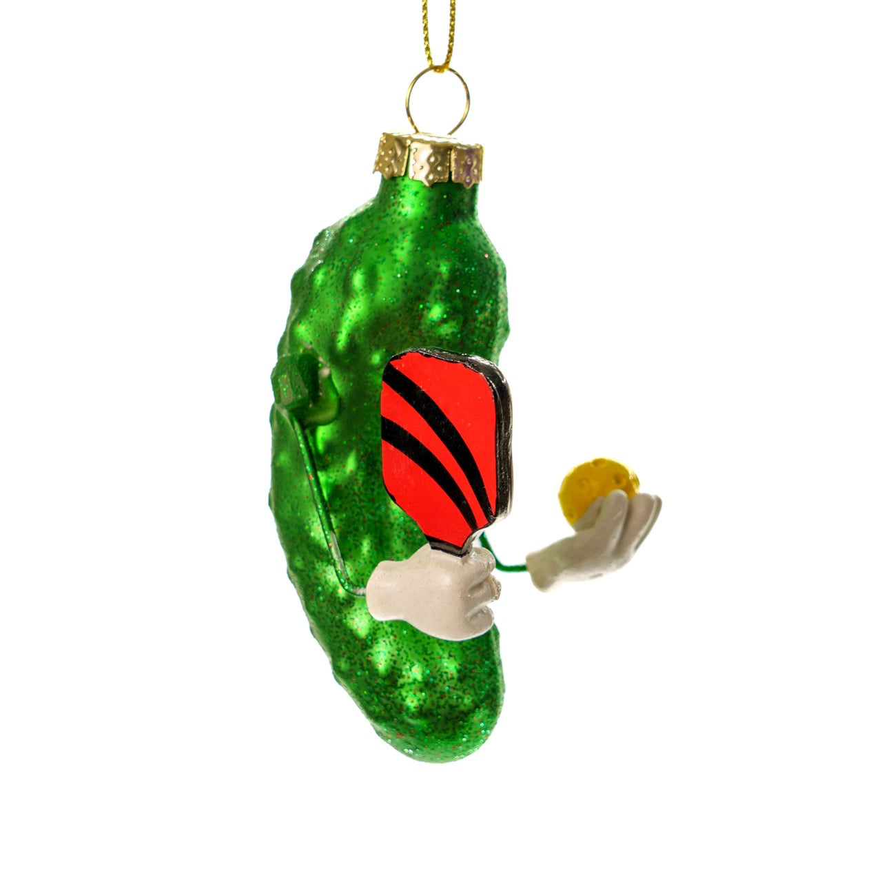 Right side of a funny handmade Kurt Adler Christmas ornament of a pickle holding a pickleball paddle and a pickleball on a white studio backdrop