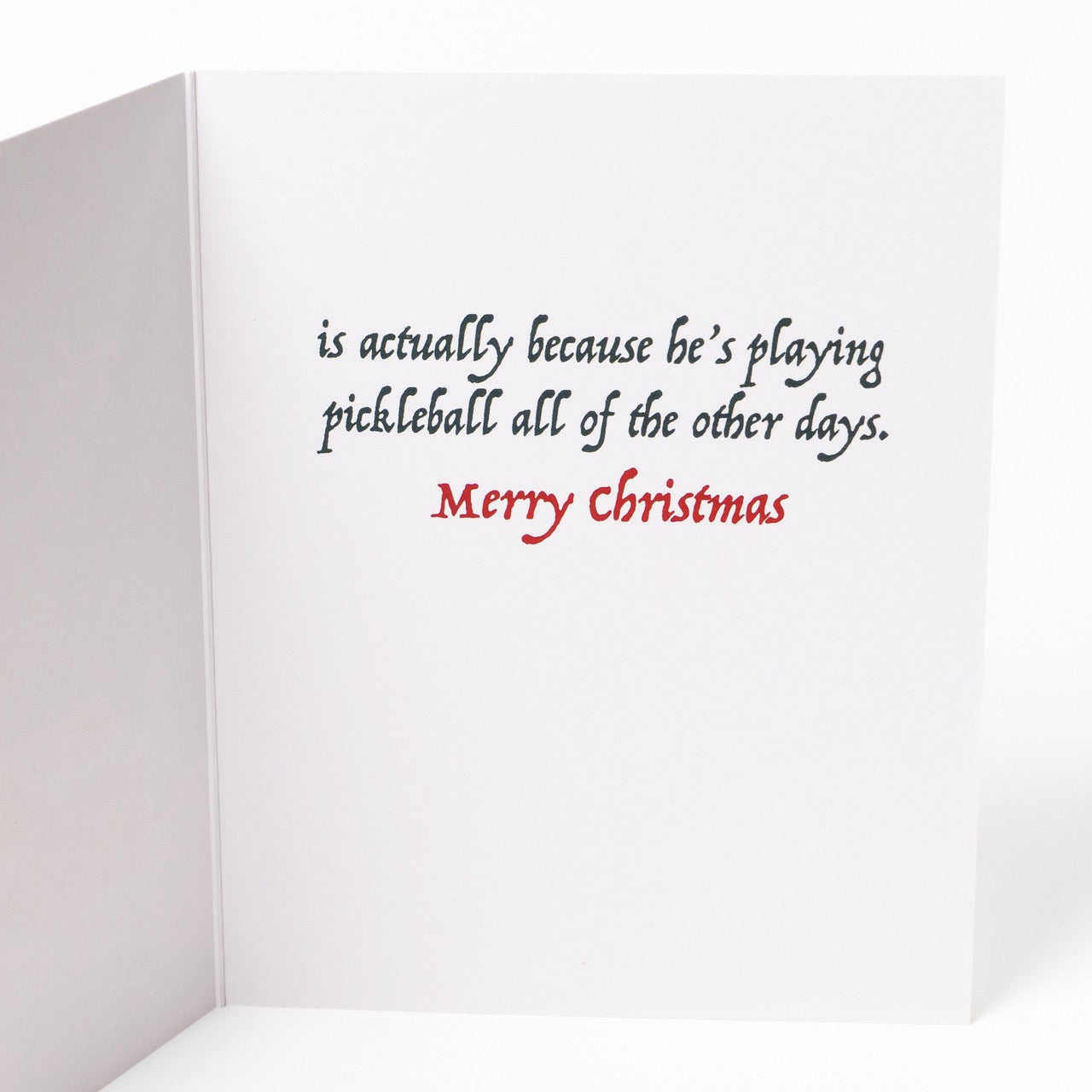 Inside message of a pickleball themed Christmas greeting card showing Santas home with a message that says &quot;The reason Santa only comes once a year... is actually because he&