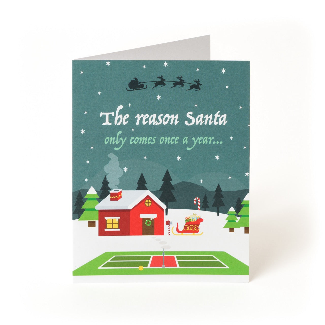 Front of a pickleball themed Christmas greeting card showing Santas home in the north pole with a pickleball court in the front with a fun festive message.