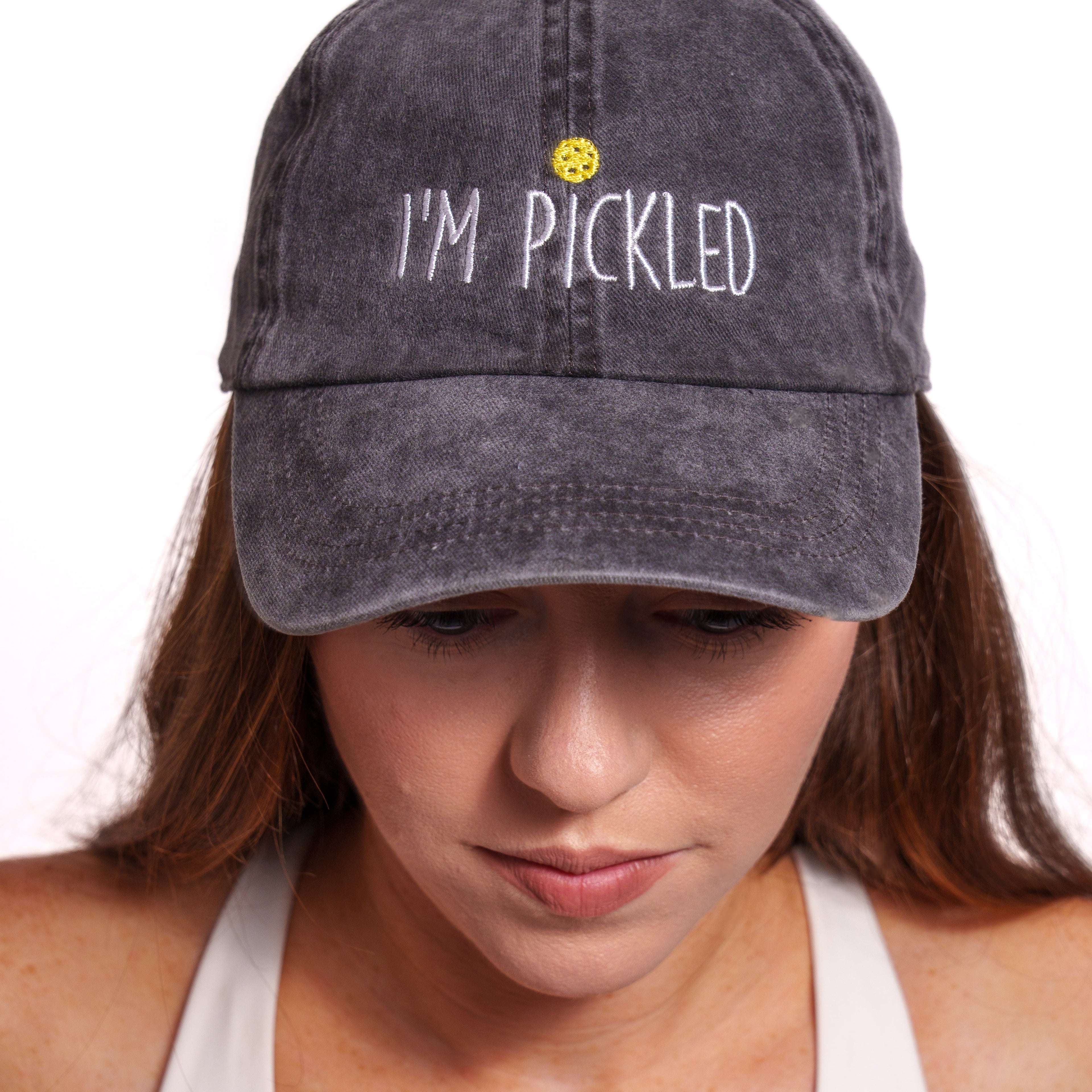 Woman wearing a washed black pickleball themed hat that says "I'm Pickled"