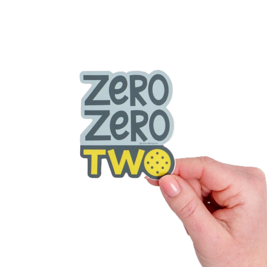 Sticker saying Zero Zero Two being held in front of white background